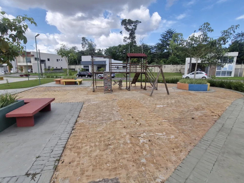 Praça do condomínio antes da reforma, com piso de terra batida e playground de madeira desgastado